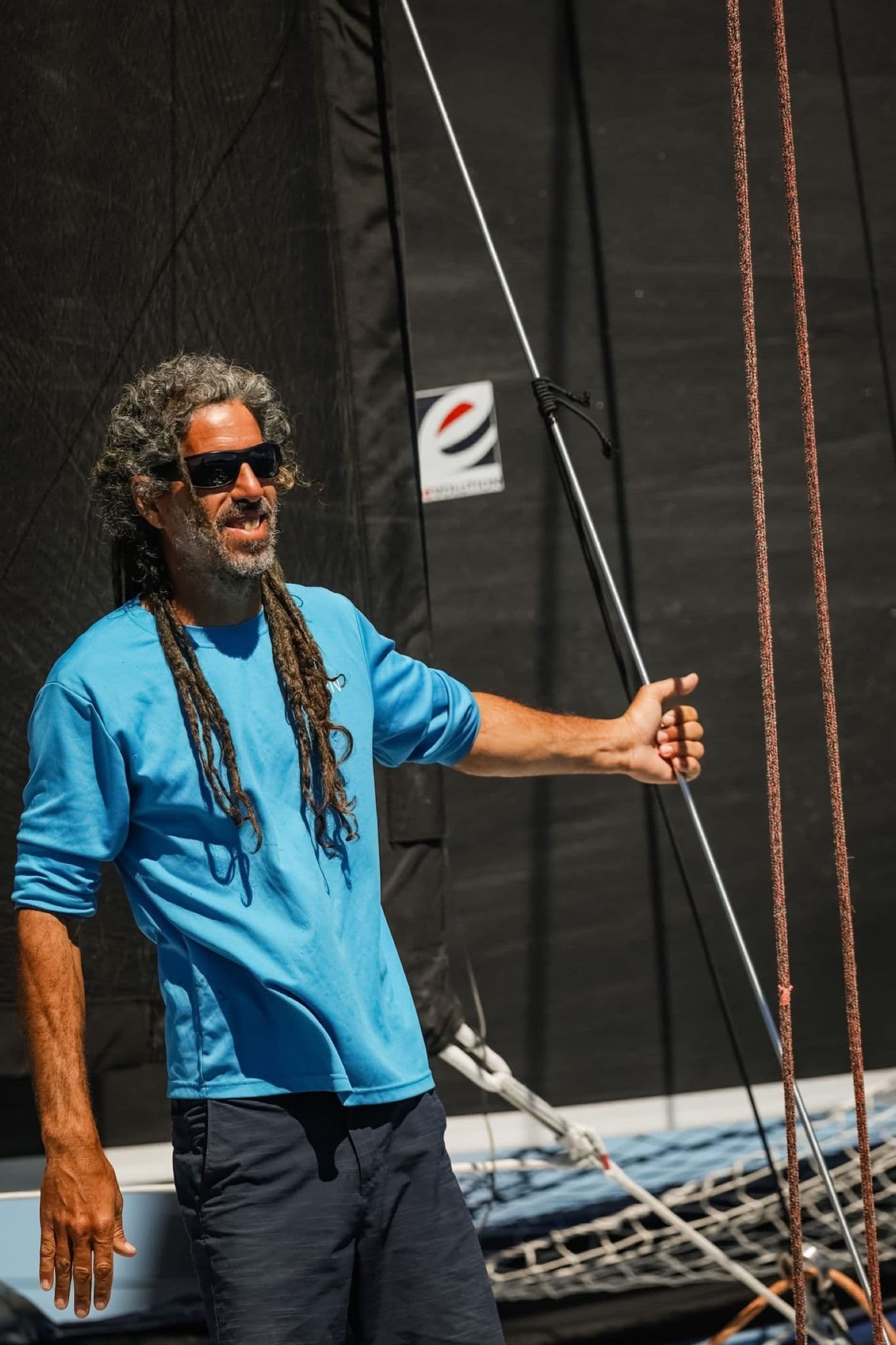 Franco standing on the foredeck of a catamaran holding a line