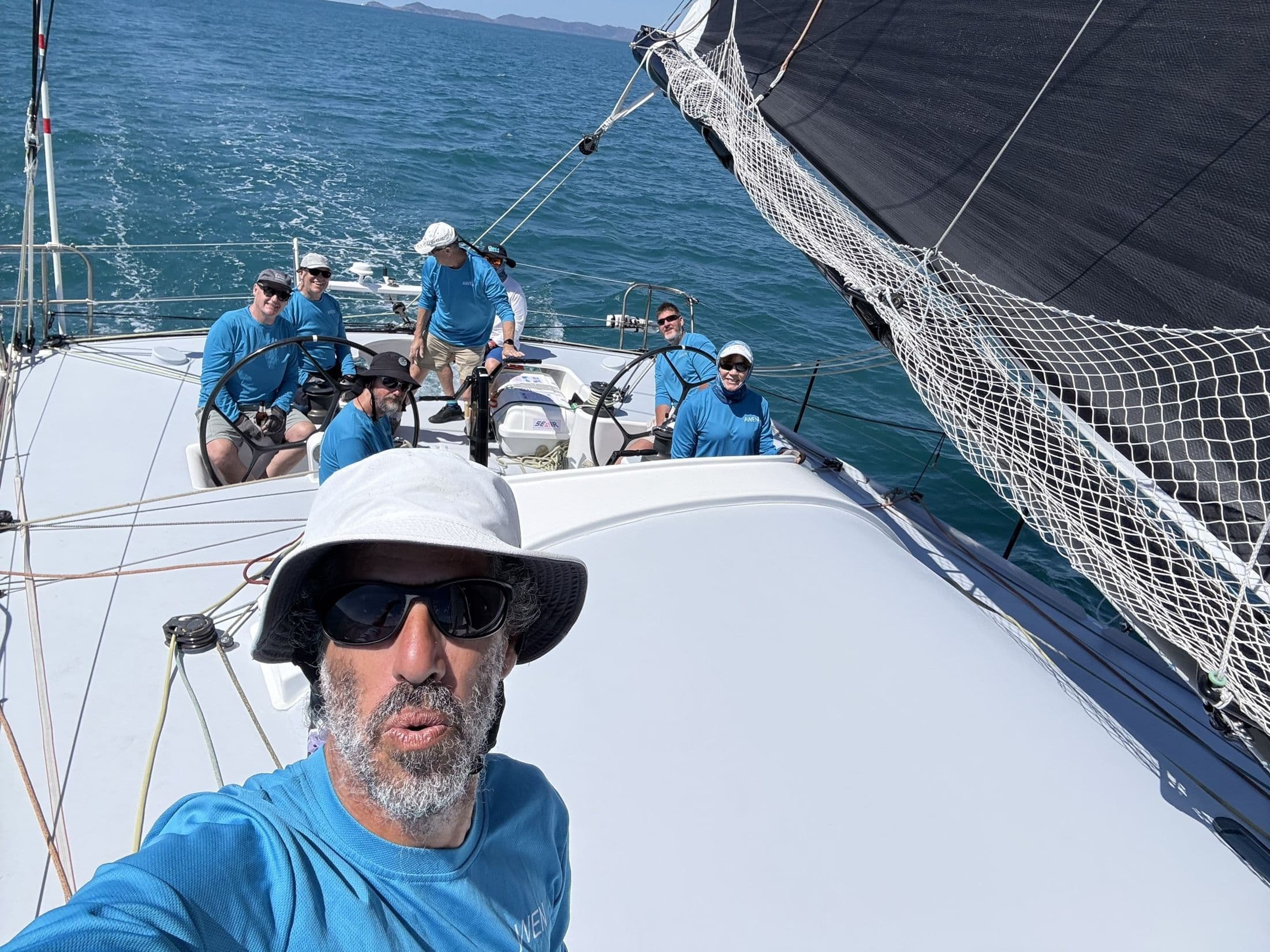 Franco in a sun hat on deck with crew behind him
